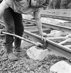 859269 Afbeelding van een wegwerker van de N.S. tijdens het leggen van spoor met zig-zag dwarsliggers.
